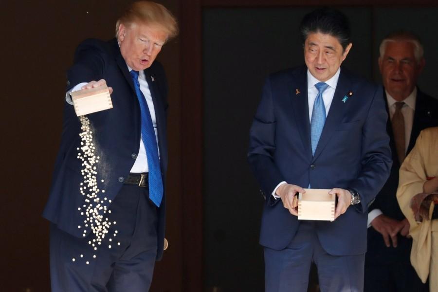 President Trump pours fish food out as Japan's Prime Minister Shinzo Abe looks on while they were feeding carps before their working lunch at Akasaka Palace in Tokyo. Donald Trump,US President Donald Trump,Donald Trump president,Donald Trump in Asia,Donald Trump Asia trip,Donald Trump Asia visit,Donald Trump Asia tour