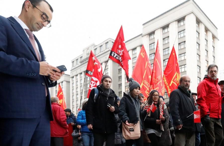 A man uses his mobile phone as demonstrators pass the State Duma, the lower house of parliament, during a rally held by Russian Communist party to mark the Red October revolution's centenary in central Moscow, Russia November 7, 2017. Russian Revolution,Bolshevik revolution,100 years since Russian Revolution,Soviet Union