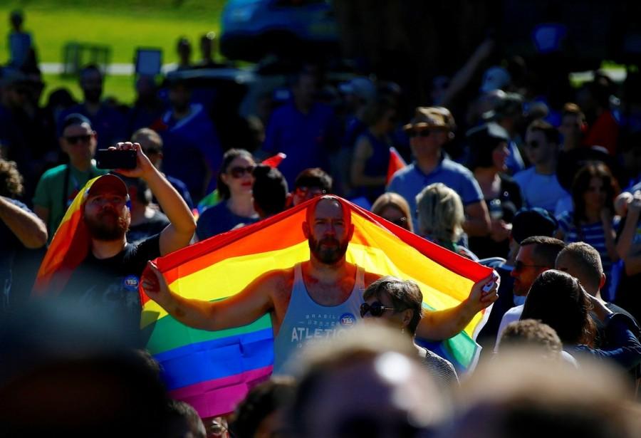 A supporter holds a flag as he celebrates at a rally in central Sydney. Same-sex marriage,same-sex marriage legalised,same-sex marriage Australia,Australians vote for same-sex marriage,vote for same-sex marriage