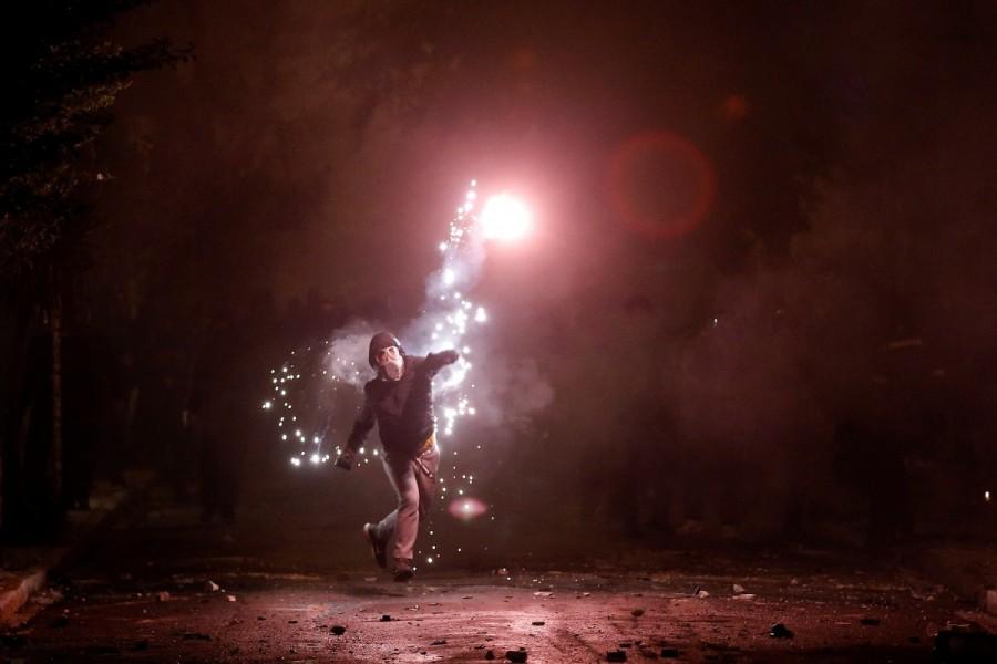 A hooded protester throws a flare during clashes following a rally marking the 44th anniversary of a 1973 student uprising against the military dictatorship that was ruling Greece, in Athens, Greece. Fiery protests,Greece,Greece protests,Protesters clash,Fiery protests in Greece