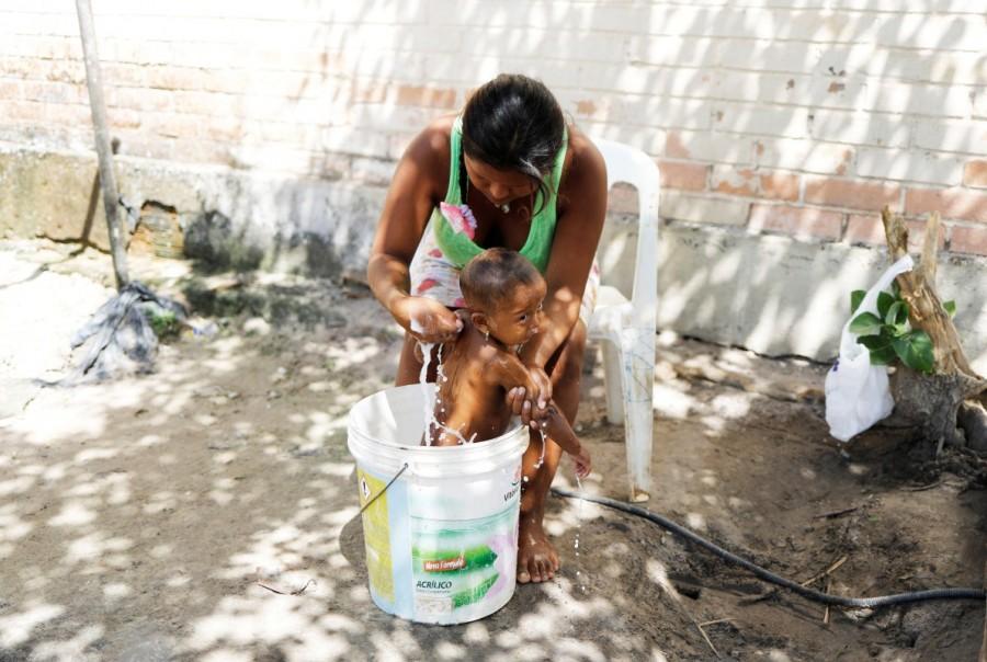 Indigenous Warao woman bathes her baby in a bucket at a shelter in Pacaraima, Roraima state, Brazil. Many went to Venezuelan cities to sell craftwork and beg on the streets. However, when the economy tipped into crisis, they began moving to Brazil last year, often just walking across the border without documents. Venezuela's indigenous,Venezuela indigenous,Venezuela,Orinoco River delta,Warao tribe