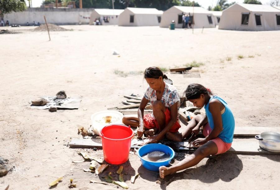 Indigenous Warao women cut fish in front of tents at a shelter in Boa Vista, Roraima state, Brazil. Venezuela's indigenous,Venezuela indigenous,Venezuela,Orinoco River delta,Warao tribe