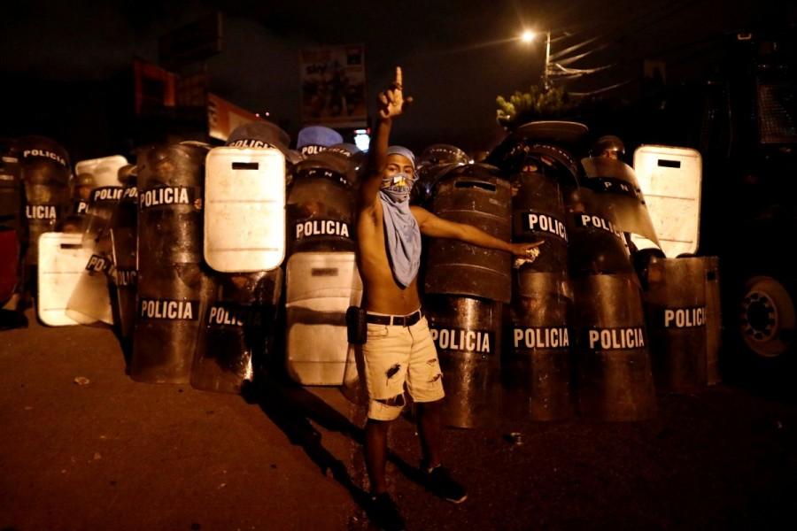 A supporter of Salvador Nasralla, presidential candidate for the Opposition Alliance Against the Dictatorship, gestures in front of riot police while he waits for official presidential election results outside the warehouse of the Supreme Electoral Tribunal in Tegucigalpa, Honduras November 30, 2017. Escalating election crisis,Honduran police,Honduras