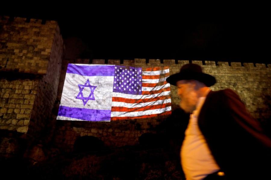 A man walks by as the Israeli national flag and an American one are projected on a part of the walls surrounding Jerusalem's Old City. Donald Trump,President Donald Trump,Jerusalem decision,Jerusalem,jerusalem violence