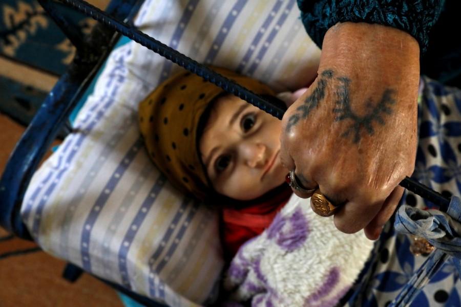 Hedla Gocmen rocks her granddaughter's cradle at their home in Dikmen village near Kiziltepe, a town in southeastern province of Mardin, Turkey, November 20, 2017. Tattooed women,Ayse Yusufoglu,Turkey women