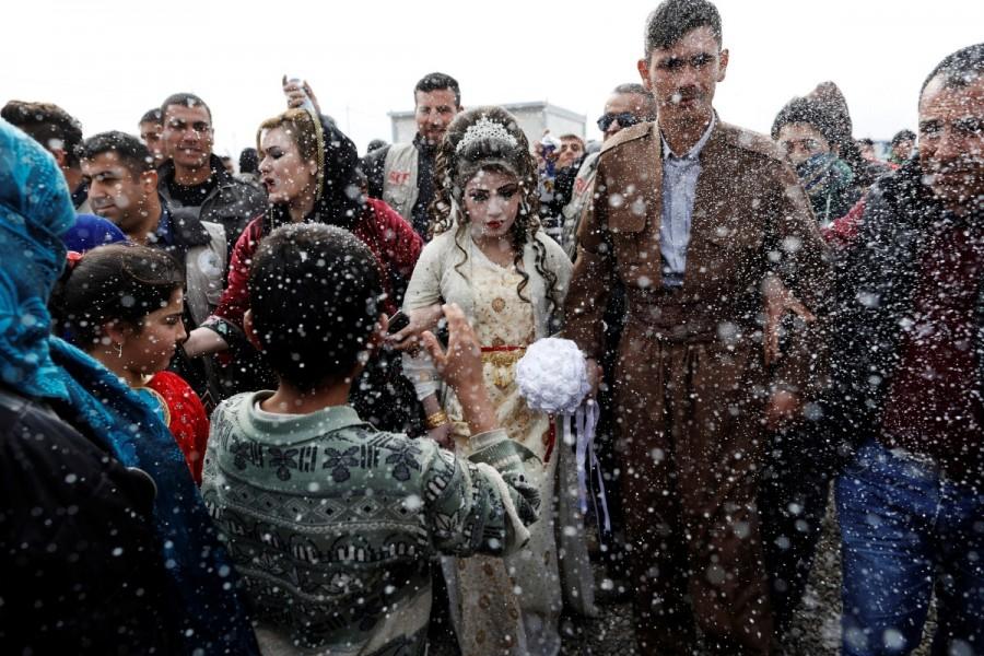 Iraqi newlyweds who fled Mosul, Hussain Zeeno Zannun (R) 26, and Chahad, 16, are showered in foam during their wedding party at Khazer camp in Iraq February 16, 2017. Zohra Bensemra,Reuters photojournalist,Guardian newspaper,Islamic State,Rohingya refugee crisis