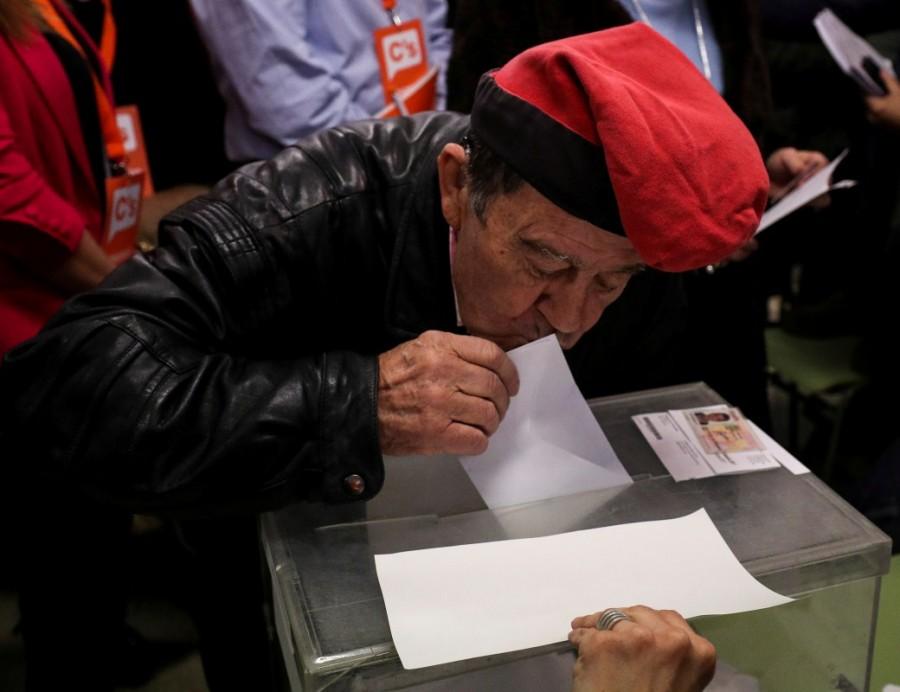 A man wearing a "barretina", the traditional Catalan hat, kisses his ballot while voting in Catalonia's regional elections at a polling station in Barcelona, Spain December 21, 2017. Catalan separatists win vote,Catalan separatists,Spanish Prime Minister Mariano Rajoy,Mariano Rajoy