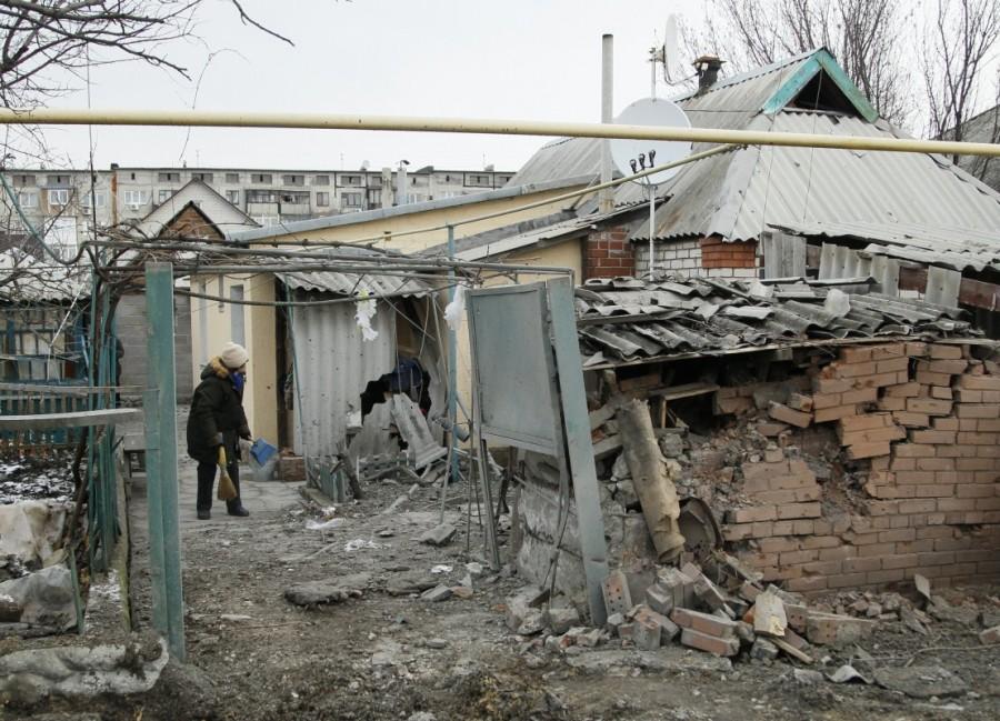 A woman cleans up debris near her house damaged by recent shelling in the rebel-held town of Yasynuvata, Ukraine December 21, 2017. Ukraine,Ukraine winter