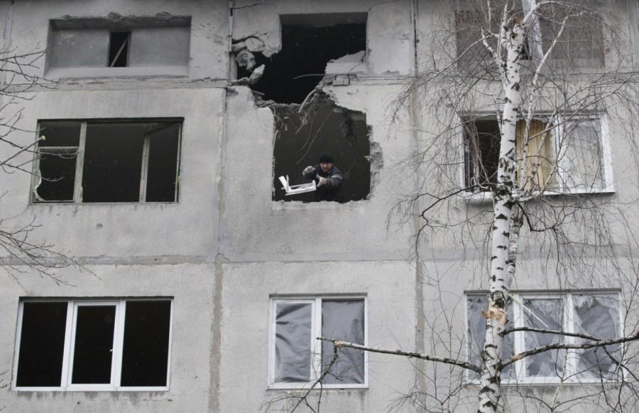 A man removes debris at a residential block damaged by recent shelling in the rebel-held town of Yasynuvata, Ukraine December 21, 2017. Ukraine,Ukraine winter