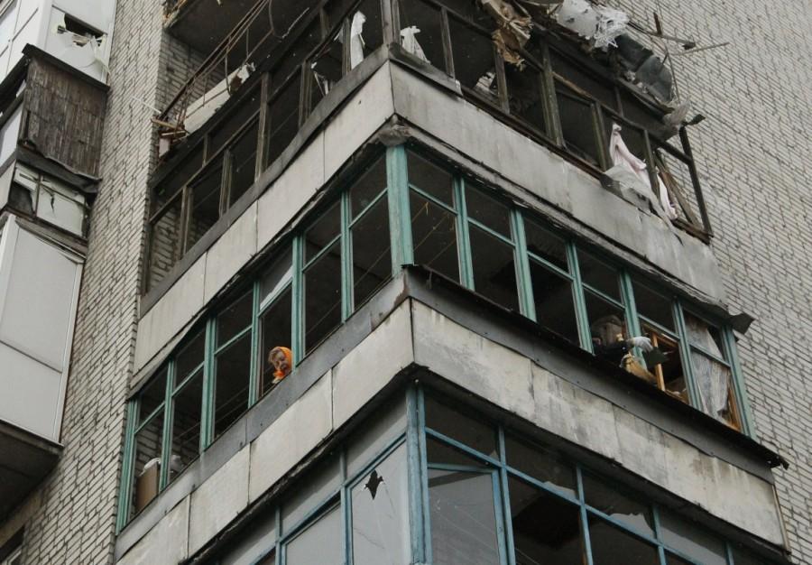 People clean their balcony at a residential block damaged by recent shelling in the rebel-held town of Yasynuvata, Ukraine December 21, 2017. Ukraine,Ukraine winter