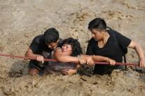A woman is assisted while crossing a flooded street after the Huaycoloro river flooded its banks, sending torrents of mud and water rushing through the streets in Huachipa, Peru, March 17, 2017.