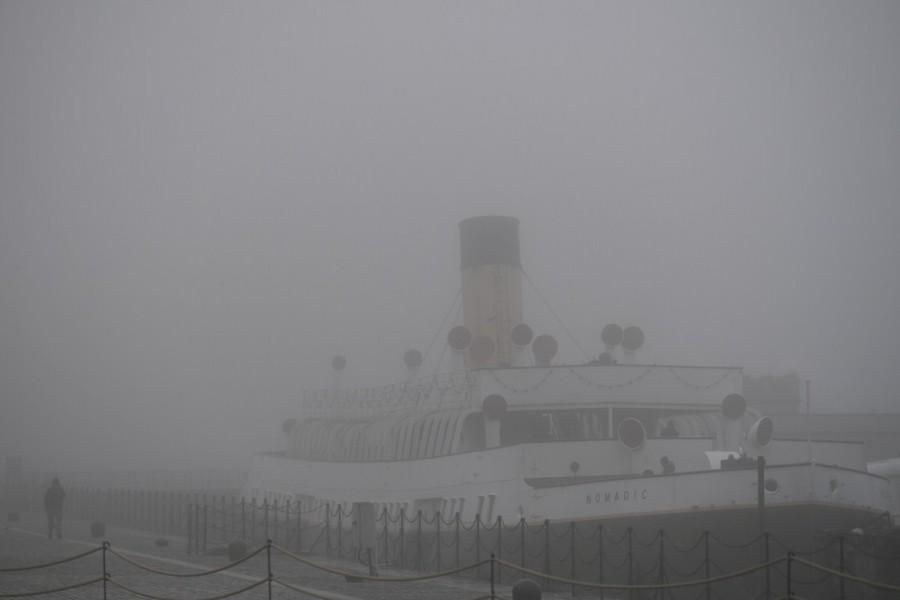 A man walks past a boat through heavy fog in Belfast, Northern Ireland, January 10, 2018. Northern Ireland,Ireland,fog,Ireland hidden in fog