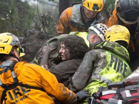 Emergency personnel carry a woman rescued from a collapsed house after a mudslide in Montecito, California, U.S. January 9, 2018.