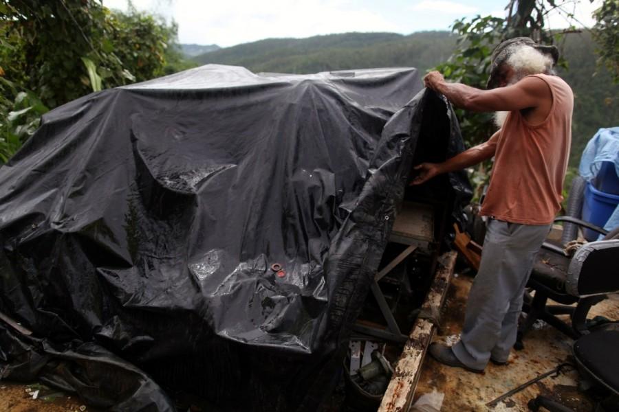 Moises Perez looks at some of his belongings covered by a tarpaulin outside his home in Naguabo. Hurricane Maria,Hurricane Maria Puerto Rico,Puerto Rico struggles,Puerto Rico,Puerto Rico electricity,Puerto Rico Hurricane Maria irma,Puerto Rico food and water