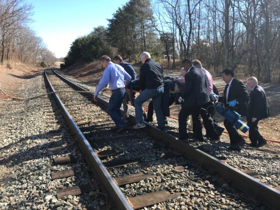 Emergency first responders and passengers carry an injured person across train tracks to an ambulance. Amtrak passenger train,Amtrak train,Virginia,Virginia road crossing,garbage truck