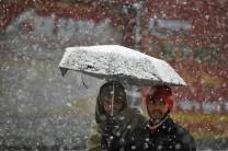 Men walk under an umbrella during snowfall on a cold winter morning in Srinagar.
