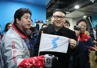 A man impersonating Kim Jong Un holds a Korean unification flag.