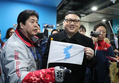 A man impersonating Kim Jong Un holds a Korean unification flag.