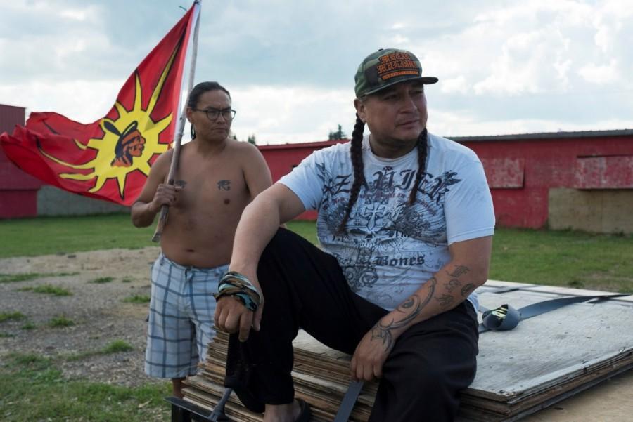 Denby Shingoose (L), founder of the Indigenous Warriors: A Youth Warrior Society, holds a flag as Stanley Cote, another founder, sits beside him in Cote First Nation, near the town of Kamsack, Saskatchewan. "Our people are killing themselves, and we have to step up and try to stop that," says Cote, a member of FNIW who has lived in both Winnipeg and Cote First Nation in Saskatchewan. "I was in the village, on Cote First Nation, when my 12-year-old niece hung (sic) herself one morning." In response, Cote founded the Youth Warrior Society. First Nations Indigenous Warriors,Indigenous Warriors,Canada,colonial policies