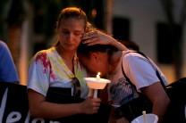 Tori Stetzer (L) and Taylor Miler, both of Parkland, react during a candlelight vigil fas they hold placards with the names of victims of the shooting in Parkland, Florida at Florida Atlantic University in Boca Raton, Florida, February 16, 2018.