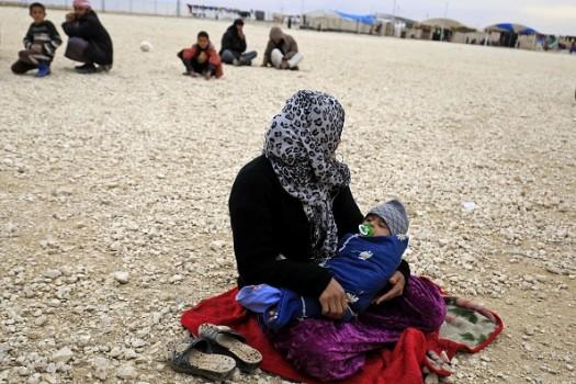 A displaced Syrian, who fled their homes in Deir Ezzor city, carries her child at a refugee camp in Syrias northeastern Hassakeh province.