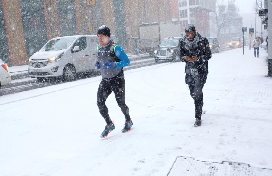 A man jogs during a snow shower in London, Britain. Arctic storm,Arctic storm in Europe,Europe,Europe cold weather,Europe Arctic storm