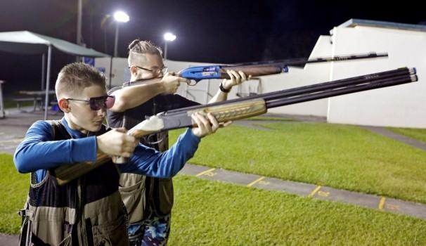 Damien Creller (L), 12, shoots during a clay target youth group shooting meeting in Sunrise, Florida.