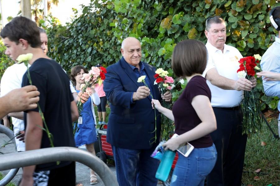 Police officers hand out carnations as students arrive at Marjory Stoneman Douglas High School for the first time since the mass shooting in Parkland, Florida, February 28, 2018. Parkland students,Parkland students returns,mass shooting,mass school shooting,Marjory Stoneman Douglas High School