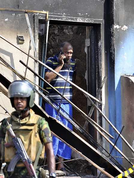 A man looks out from a burnt out home as a Sri Lankan police commando patrols on the streets of Pallekele, a suburb of Kandy, on March 6, 2018. Sri Lanka,Buddhist-Muslim clashes,Buddhist-Muslim fight,Buddhist-Muslim clashes in Sri Lanka,Sri Lanka nationwide state emergency,Sri Lanka emergency