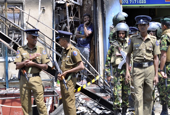 A man looks out from a burnt out home as Sri Lankan police commandos patrol on the streets of Pallekele, a suburb of Kandy, on March 6, 2018, following anti-Muslim riots that has prompted the government to declare a state of emergency. Sri Lanka,Buddhist-Muslim clashes,Buddhist-Muslim fight,Buddhist-Muslim clashes in Sri Lanka,Sri Lanka nationwide state emergency,Sri Lanka emergency
