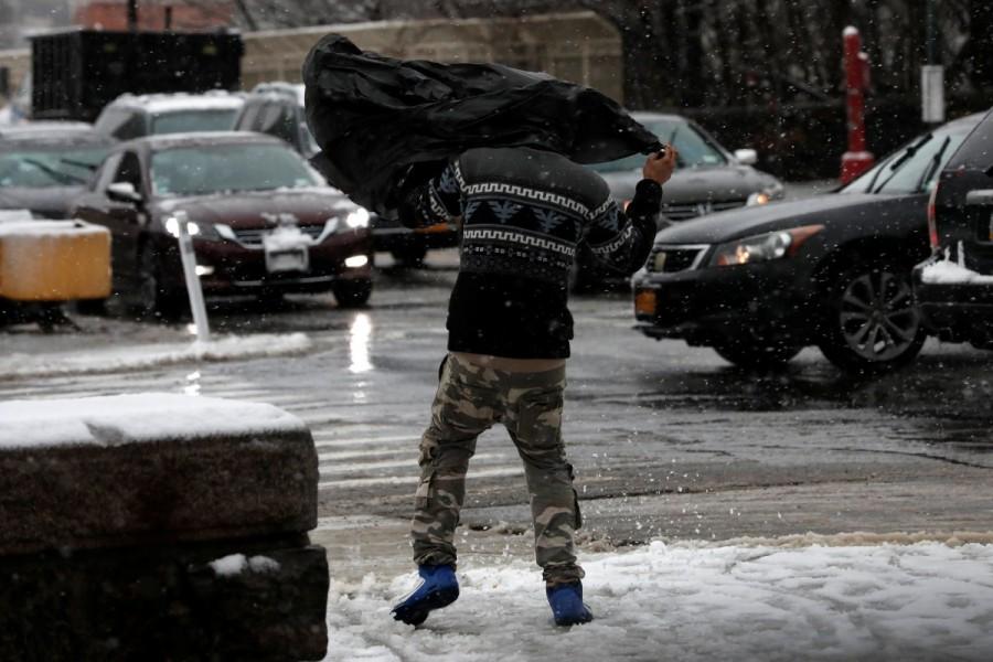 A man struggles in the wind beneath a plastic bag as he walks during a snowstorm in upper Manhattan in New York City. Winter storm,winter storm Northeast,Northeast,New York,New York snowfall