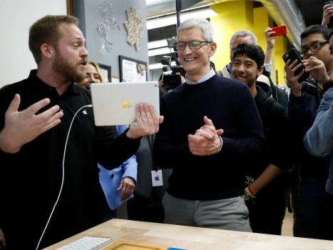 Tim Cook, Chief Executive Officer of Apple Inc., looks at a iPad, as he tours a technology lab, at an education-focused event at Lane Technical College Prep High School in Chicago, Illinois, U.S.