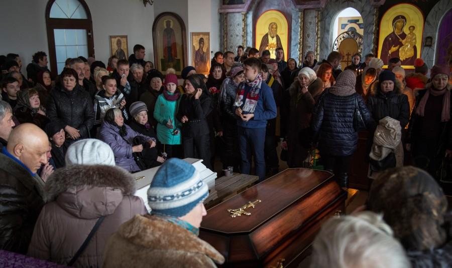 People stay next to caskets with the victims of a shopping mall fire during a funeral ceremony in cathedral in Kemerovo, Russia March 28, 2018. Mourning after Russia mall fire,Russia mall fire,russia mall fire death,russia mall fire photo,Siberian shopping mall