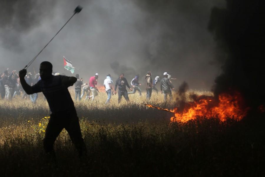 A Palestinian demonstrator uses a sling to hurl stones during clashes with Israeli troops at the Israel-Gaza border at a protest demanding the right to return to their homeland, in the southern Gaza Strip April 6, 2018. Gaza-Israel border,Israeli troops,Palestinian protesters,Gaza border