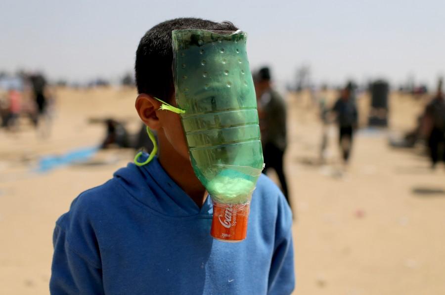 A Palestinian protects himself from inhaling tear gas at the Israel-Gaza border during a protest demanding the right to return to their homeland, in the southern Gaza Strip April 6, 2018. Gaza-Israel border,Israeli troops,Palestinian protesters,Gaza border