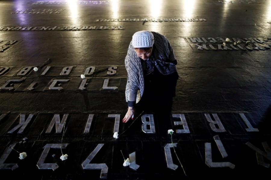 A woman places a flower next to the name of a former death camp as she visits the Hall of Remembrance at the Yad Vashem World Holocaust Remembrance Center, on the annual Israeli Holocaust Remembrance Day, in Jerusalem April 12, 2018 Holocaust Remembrance Day,Remembrance Day,Holocaust Remembrance Day pics,Holocaust Remembrance Day images,Israel stands silent