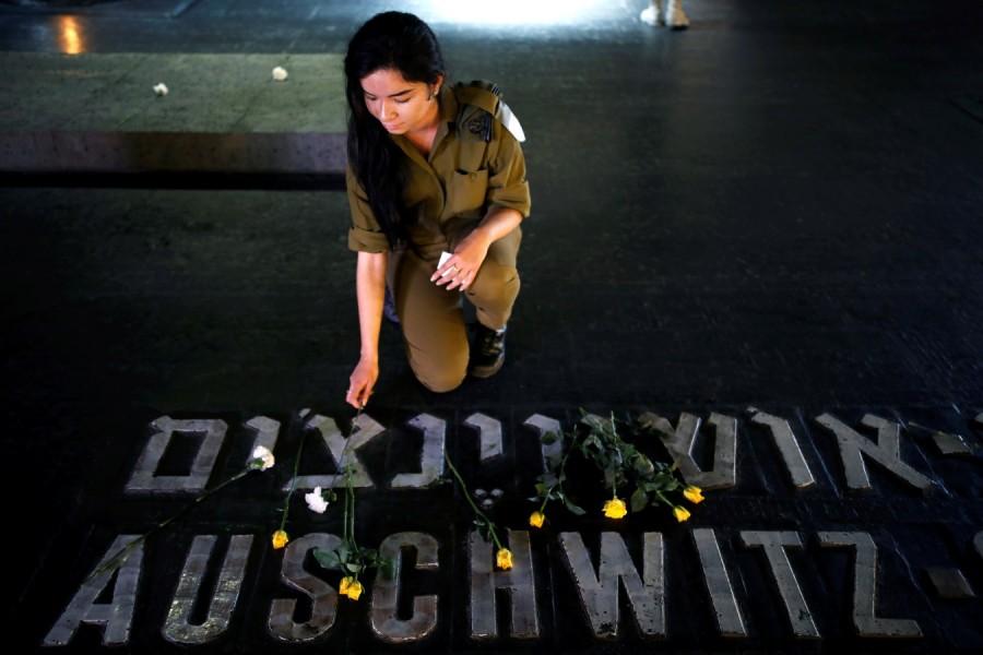 An Israeli soldier places a flower next to the name of a former death camp as she visits the Hall of Remembrance at the Yad Vashem World Holocaust Remembrance Center, on the annual Israeli Holocaust Remembrance Day, in Jerusalem April 12, 2018. Holocaust Remembrance Day,Remembrance Day,Holocaust Remembrance Day pics,Holocaust Remembrance Day images,Israel stands silent