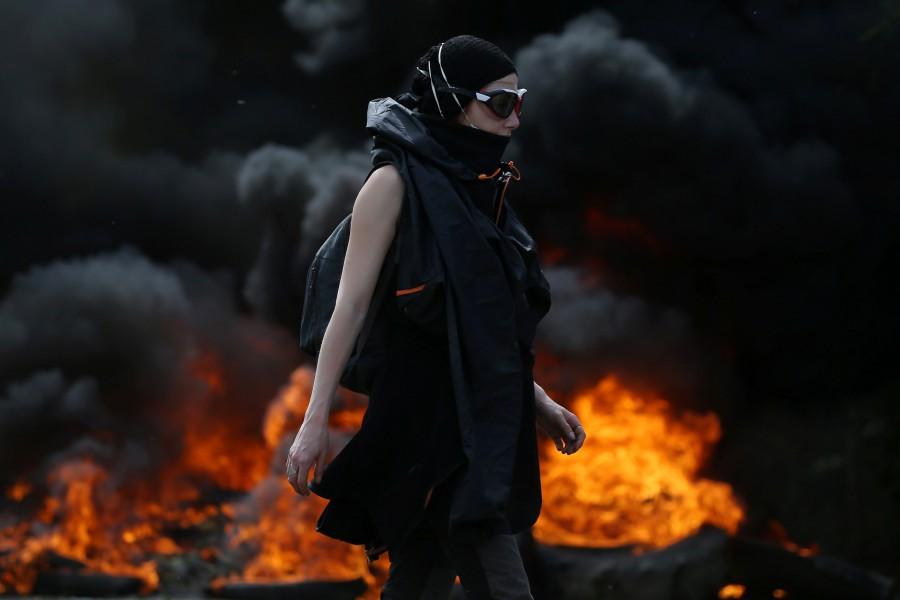 A protester walks near burning debris that barricades a road as French gendarmes continue an evacuation operation in the zoned ZAD (Deferred Development Zone) at Notre-Dame-des-Landes, near Nantes, France, April 12, 2018. French police,eco-activists,western France,French police swoop