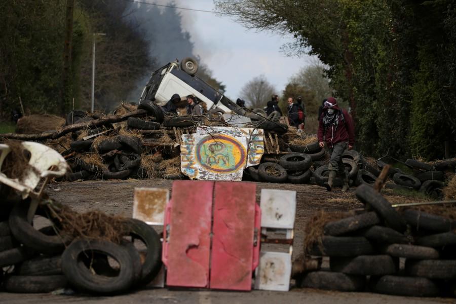Protesters stand with debris that barricades a road as French gendarmes continue an evacuation operation in the zoned ZAD (Deferred Development Zone) at Notre-Dame-des-Landes, near Nantes, France, April 12, 2018. French police,eco-activists,western France,French police swoop