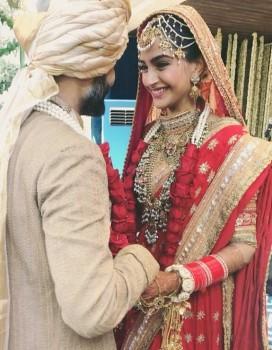 Actress Sonam Kapoor, who has earned the 'fashionista' tag in Bollywood with her experimental taste, chose a traditional bright red lehenga with heavy jewellery for her wedding day as she tied the knot with long-time beau Anand Ahuja at a ceremony here on Tuesday morning. Sonam wore a lotus-motif ensemble by designer Anuradha Vakil and looked every bit the Punjabi bride with her hands adorned by a deep maroon colour of henna, both wrists full of the 'chooda' and 'kaleere'. She wore a statement maatha-patti.