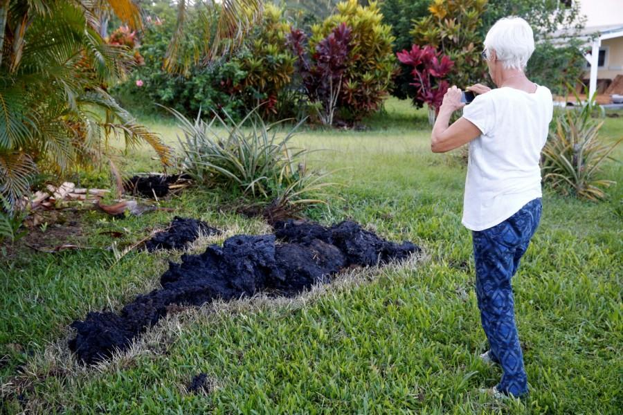 Patricia Spinoza, of Puna, takes a photo of lava on a lawn on the outskirts of Pahoa during ongoing eruptions of the Kilauea Volcano in Hawaii, U.S., May 14, 2018. Hawaiian volcano,Hawaiian volcano pics,Hawaiian volcano images