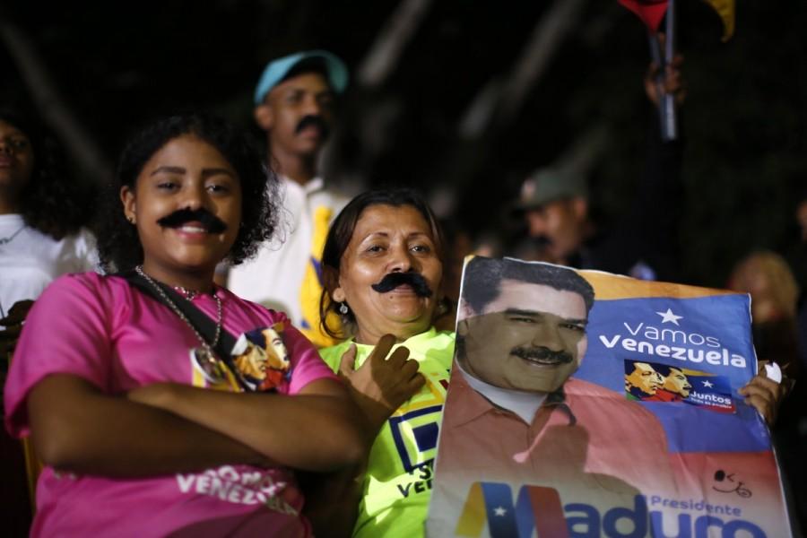 Female supporters wear mustaches depicting Venezuela's President Nicolas Maduro while he speaks during a gathering after the results of the election were released, outside of the Miraflores Palace in Caracas, Venezuela, May 20, 2018. Nicolas Maduro,President Nicolas Maduro,Nicolas Maduro re-elected