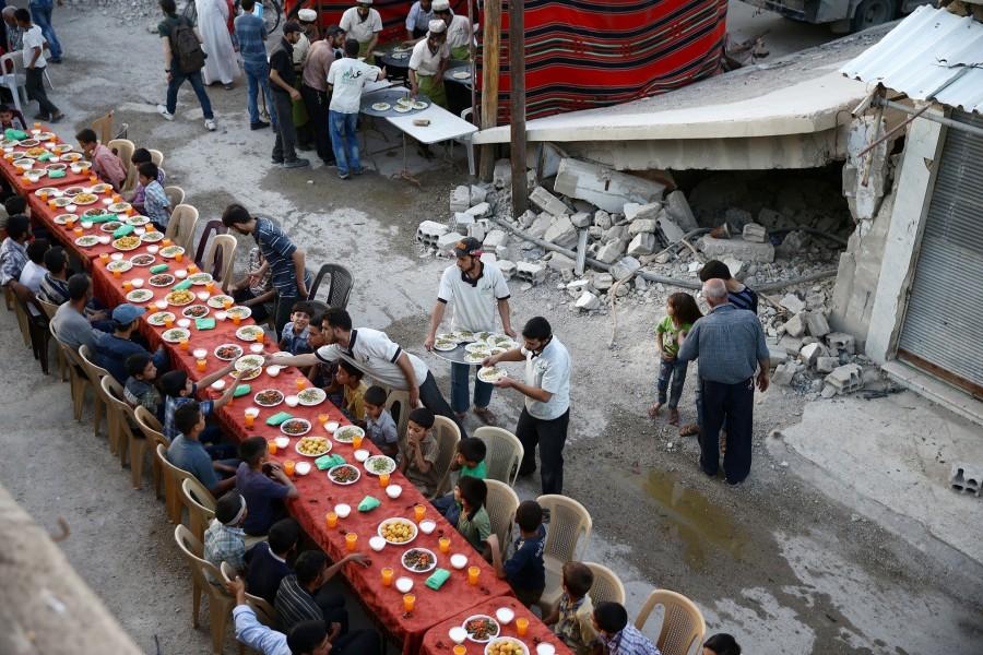 People gather for Iftar (breaking fast), organised by Adaleh Foundation, amidst damaged buildings during the holy month of Ramadan in the rebel held besieged Douma neighbourhood of Damascus, Syria. Ramadan 2018,Ramadan,happy Ramadan,Ramadan fasting,breaking their fast,people breaking their fast,Ramadan 2018 pics,Ramadan 2018 images,Ramadan 2018 stills,Ramadan 2018 pictures,iftar,ramadan iftar