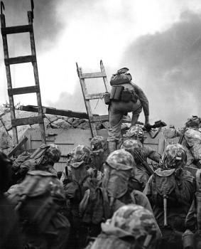 First Lieutenant Baldomero Lopez of the U.S. Marine Corps leads the 3rd Platoon, Company A, 1st Battalion, 5th Marines over the seawall on the northern side of Red Beach as the second assault wave lands on Inchon, September 15, 1950. Lt. Lopez was killed in action a few minutes later while assaulting a North Korean bunker.