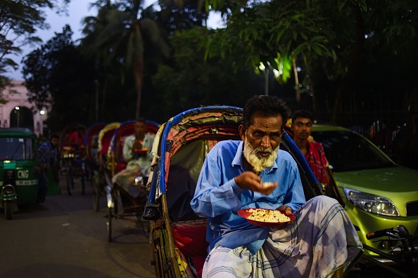 A Bangladeshi rickshaw puller breaks his fast during the holy month of Ramadan at a shrine in Dhaka on May 27, 2018. - Muslims throughout the world are marking the month of Ramadan, the holiest month in the Islamic calendar during which Muslims fast from dawn until dusk. Ramadan 2018,Ramadan,Iftar meals,Ramzan Id,Eid-ul-Fitar,Eid-ul-Fitar 2018,Ramadan meals