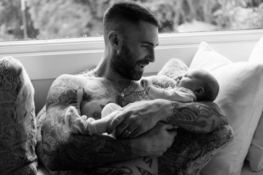 Behati Prinsloo has shared an adorable first glimpse of her and Adam Levine's newborn. The Victoria's Secret model, on the occasion of Father's Day, posted a picture of the 'Maroon 5' frontman cradling baby Gio in his arms. 