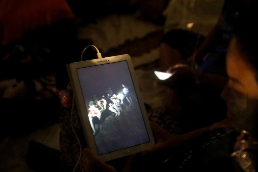 A family member looks at a photo near Tham Luang cave complex, as members of under-16 soccer team and their coach have been found alive according to a local media's report in the northern province of Chiang Rai, Thailand, July 2, 2018. Missing youth soccer team,soccer team found alive,Missing boys found alive,Thailand cave,Tham Luang cave