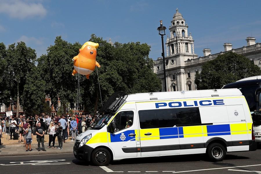 Demonstrators float a blimp portraying U.S. President Donald Trump, behind a police vehicle in Parliament Square, during the visit by Trump and First Lady Melania Trump in London, Britain July 13, 2018. Trump Baby,Trump baby balloon,Donald Trump,Donald Trump ballon,Donald Trump ballon pics,Donald Trump ballon images,Donald Trump ballon stills,Donald Trump ballon pictures,Donald Trump ballon photos