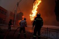 Firefighters and soldiers try to extinguish a wildfire burning in the town of Rafina