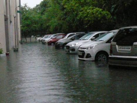 A car wades through water logged street after a heavy downpour in New Delhi